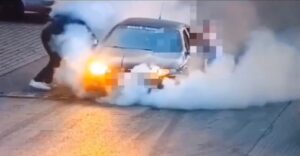 kierowca seata pali gumy_ samochód przytrzymują inne osoby_ wokół unosi się gęsty biały dym