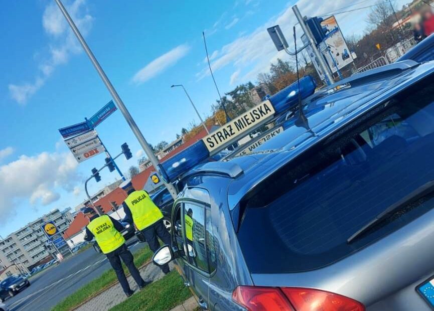 Wspólny patrol Policji i Straży Miejskiej w rejonie cmentarza w Nowym Sączu. Na pierwszym planie samochód Straży Miejskiej.